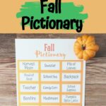 Top part of image has black text on orange and green background that says Free Printable Game Fall Pictionary. Below that is a photo of a sheet of prompt cards on a table. A decorative little pumpkin and gourd nearby.