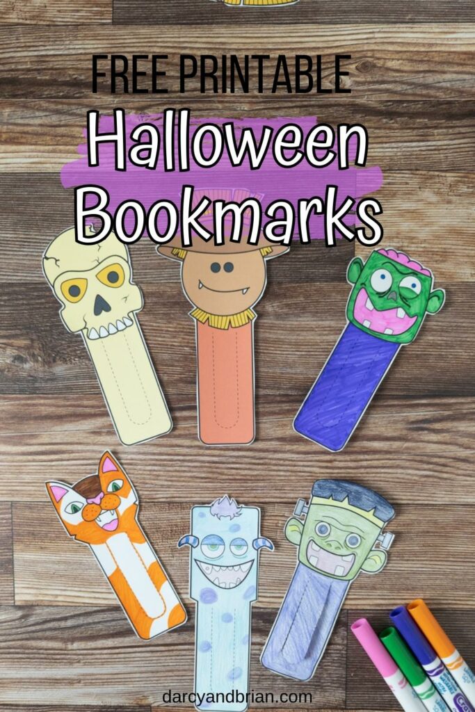 Overhead view of six different Halloween bookmarks cut out and arranged on table next to markers. Two are full color versions and the rest were colored in.