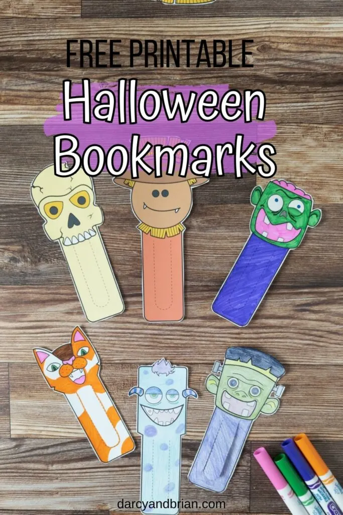 Overhead view of six different Halloween bookmarks cut out and arranged on table next to markers. Two are full color versions and the rest were colored in.