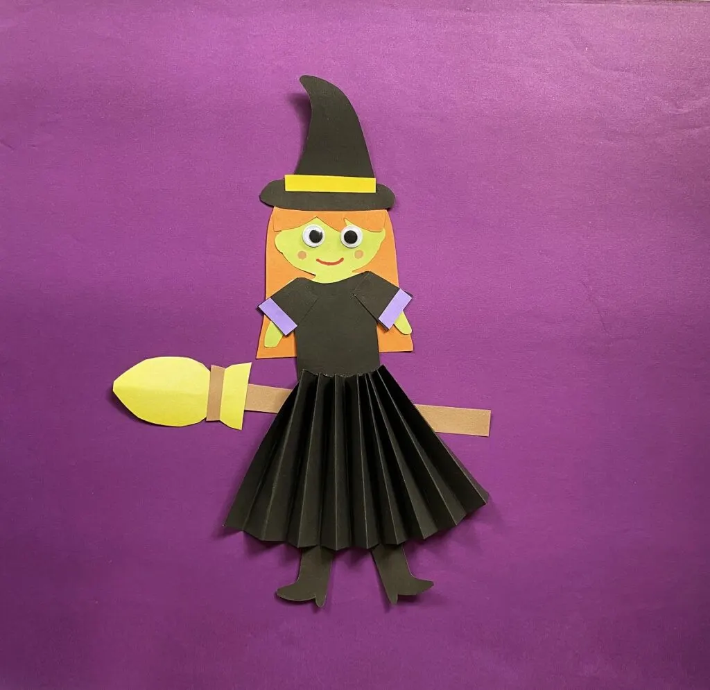 Paper witch sitting on a broom. A Halloween craft for kids.