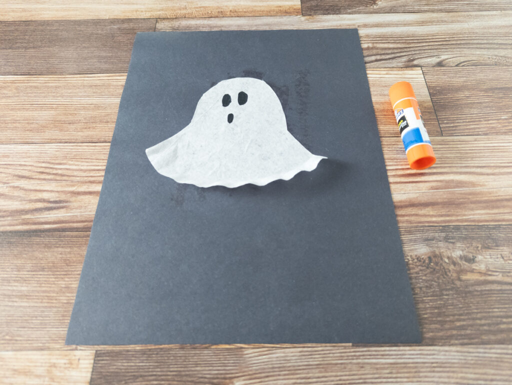 White coffee filter cut in a ghost shape and glued to black paper.