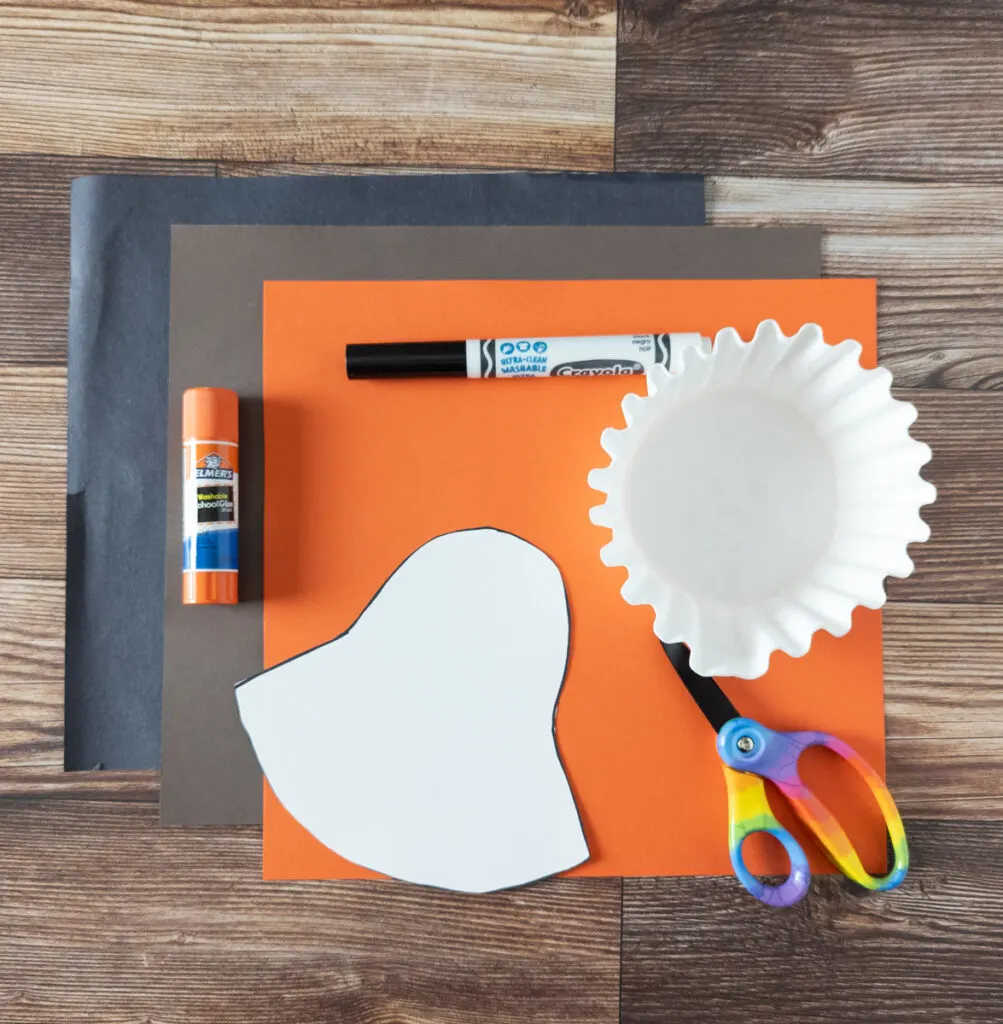 Black, brown, and orange sheets of paper, glue stick, black marker, white coffee filters, cut out craft template, and scissors.