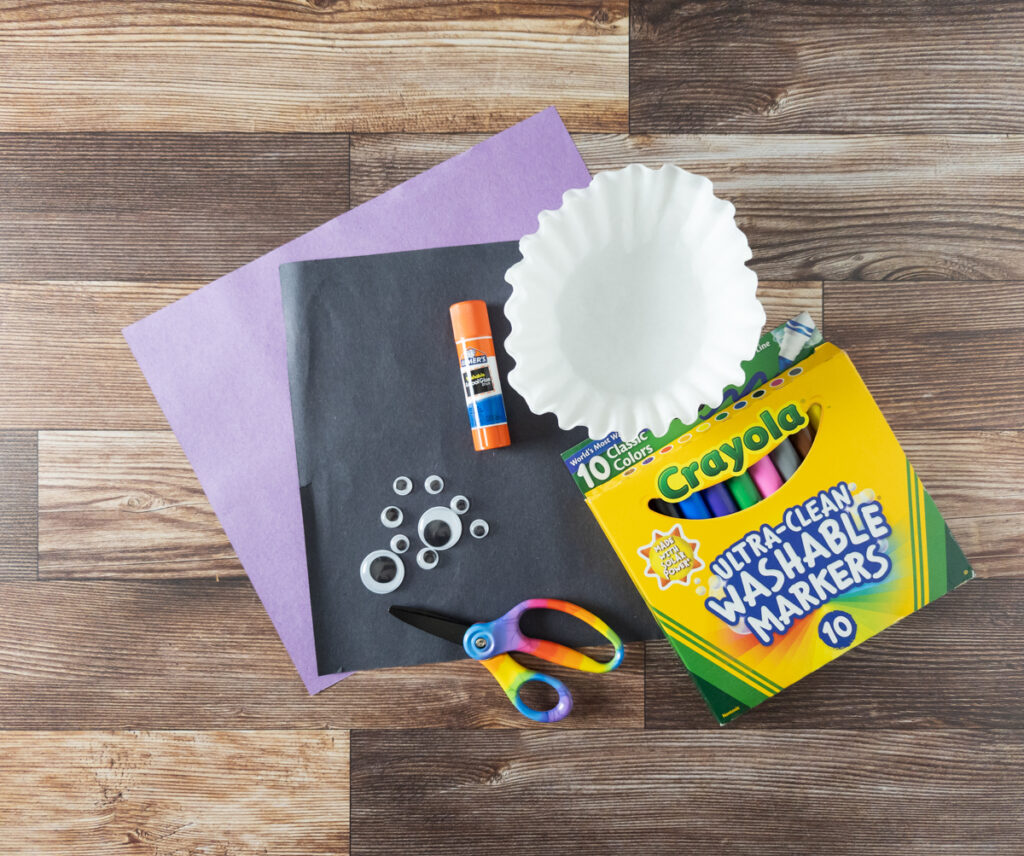 Construction paper, coffee filters, glue stick, wiggle eyes, scissors, and markers laying on table.