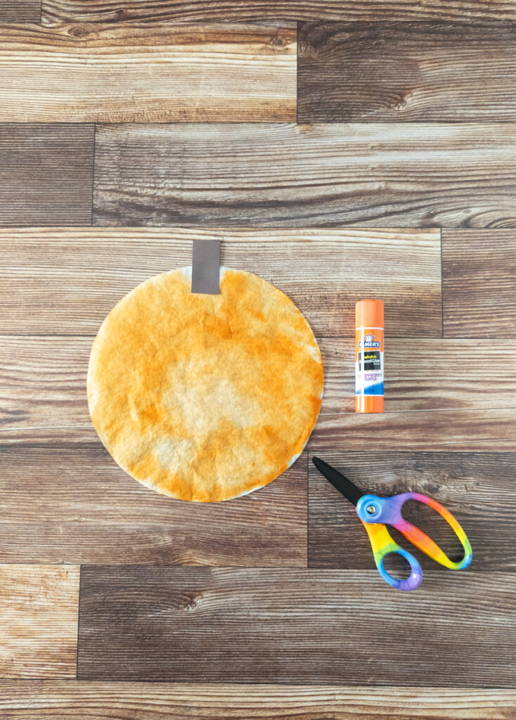 Orange colored coffee filter with brown paper glued on for stem.