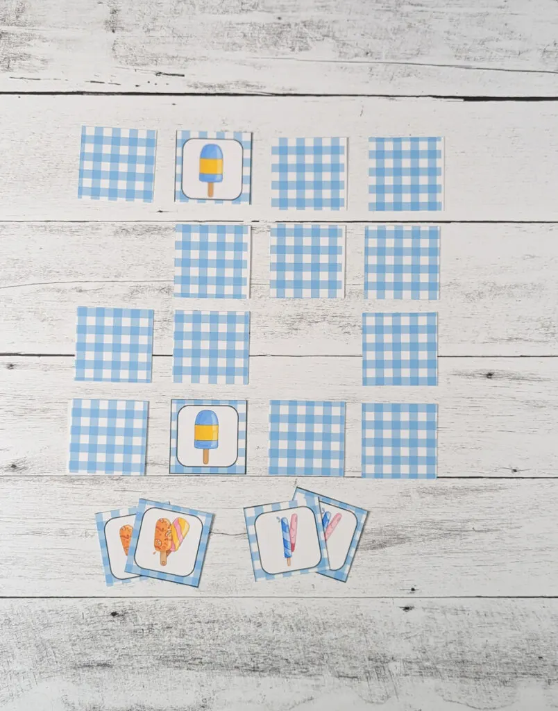 Several cards laying face down arranged in a square. A couple spots are empty and a matching pair is flipped up. A couple matching pairs lay underneath the array.