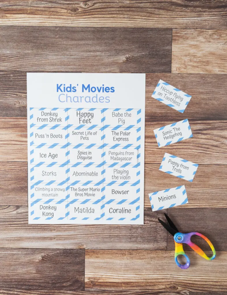 A page of movie charades printed out. Next to it are a few cards that were cut out from another page and a pair of scissors.