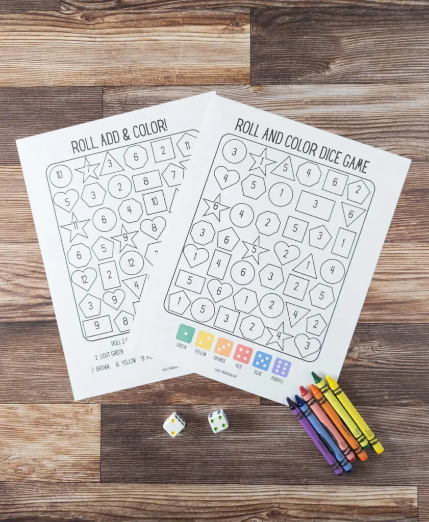 Blank roll and color dice game pages printed out and not colored yet. Dice and crayons lay next to the papers.