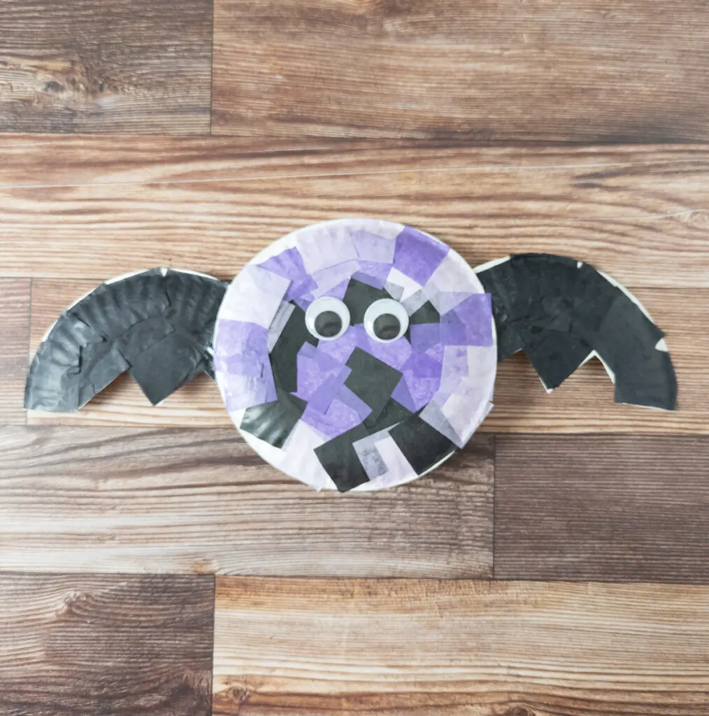 Tissue paper covered paper plate with two googly eyes glued to it for a cute bat craft.