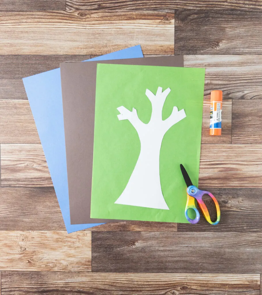 Blue and brown construction paper, green tissue paper, tree template cut out of white cardstock, scissors and glue stick.