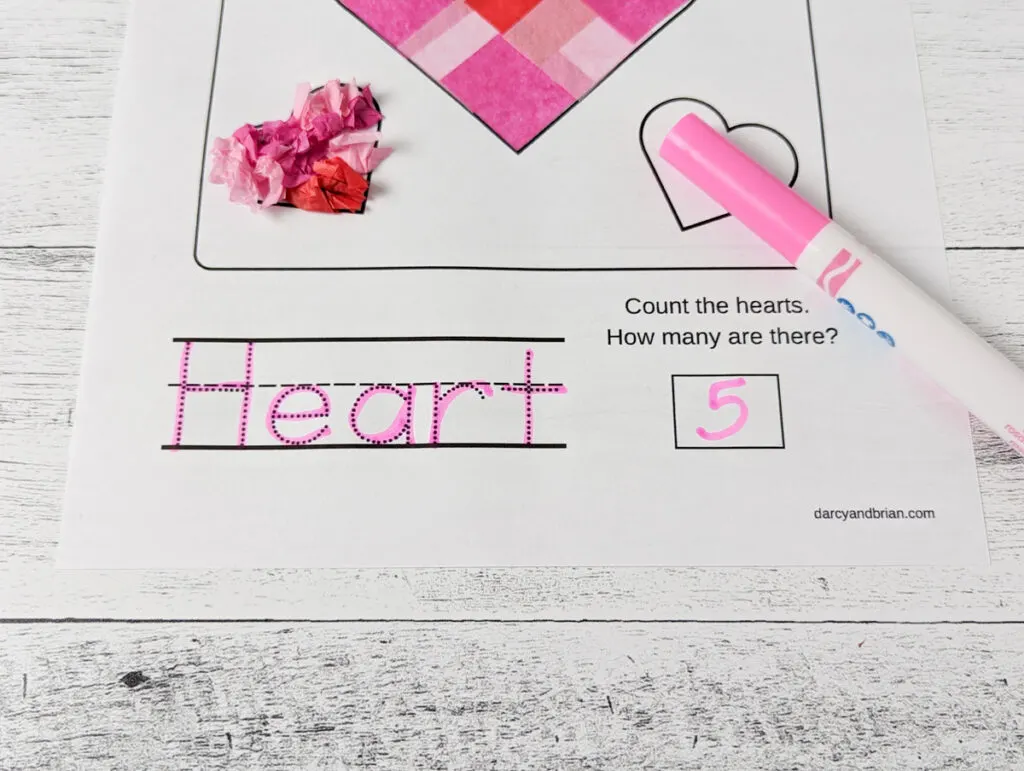 Close view of the word heart traced with a pink marker and the number 5 written in the answer box.