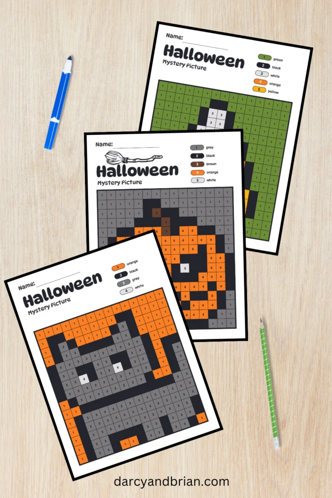 Mockup of three Halloween pixel art pictures with colors filled in on a desk background.