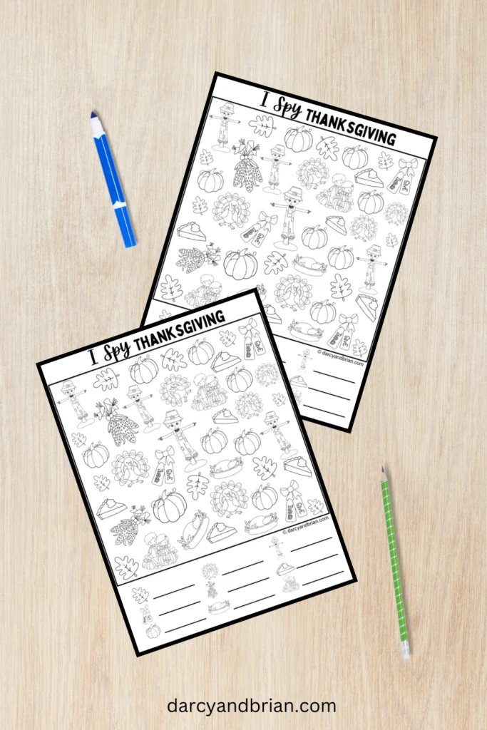Mockup of the black and white I Spy Thanksgiving coloring page on a desk with a marker and pencil. The page is shown twice.