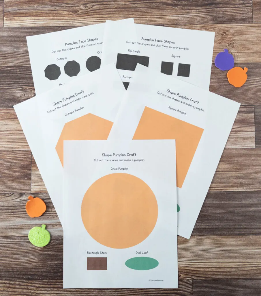 Shape pumpkin craft printable pages fanned out on table next to colorful foam pumpkin stickers.
