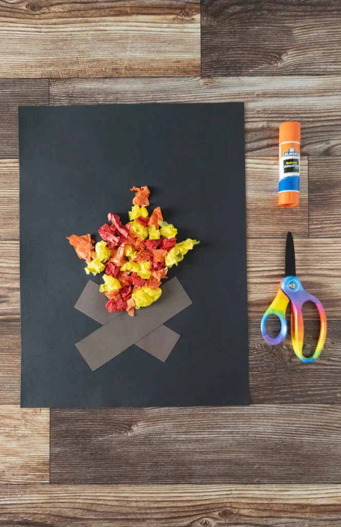 More pieces of yellow, red, and orange tissue paper glued onto paper in the shape of campfire flames.