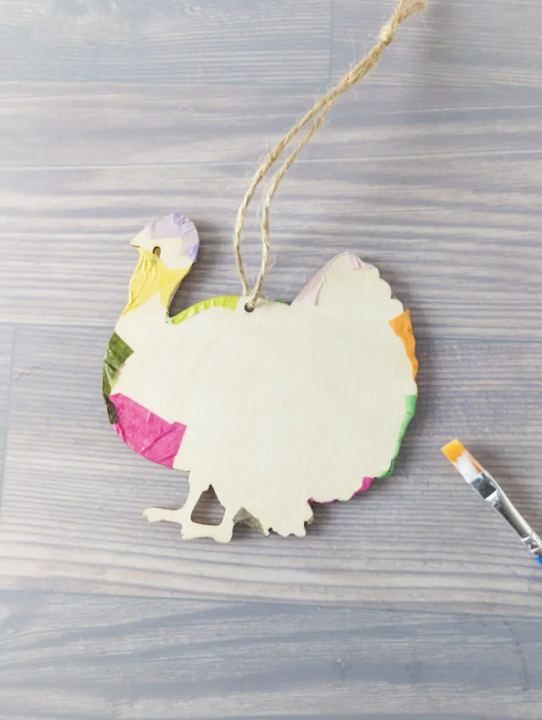 Showing how project looks when gluing and smoothing tissue paper around the edges of the turkey ornament.
