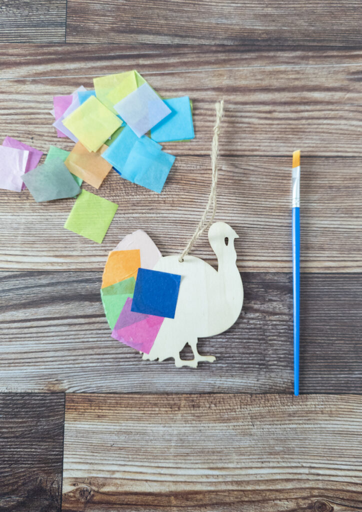 Different colors of tissue paper squares glued onto turkey wood cutout.