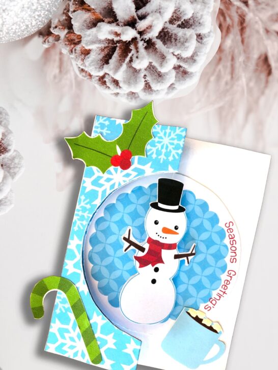 Mockup of completed snowman Christmas card on a snowy background.