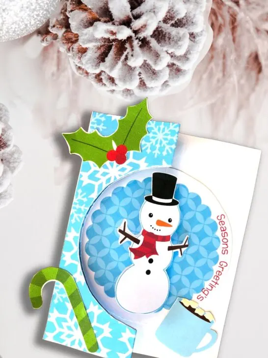 Mockup of completed snowman Christmas card on a snowy background.