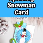 White text on blue background at the top says Spinning Snowman Card. Mockup of completed Christmas card on a snowy background.