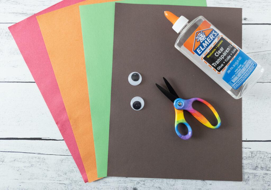 Assorted colors of construction paper, googly eyes, scissors, and a bottle of glue.