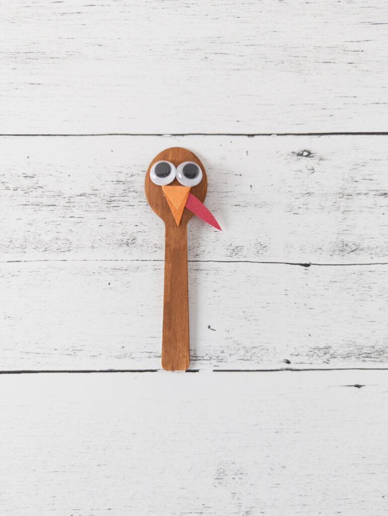 Brown painted spoon with turkey's faced glued on.
