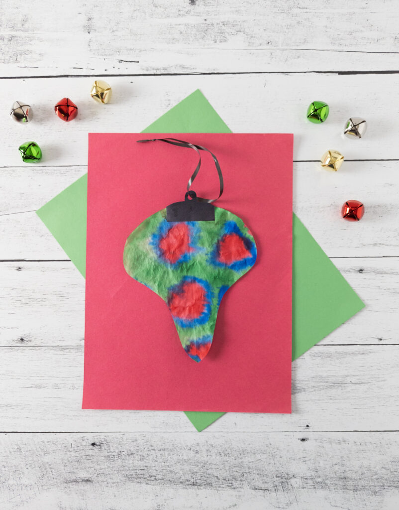 Coffee filter ornament colored green, red, and blue and cut into a bulb shape.