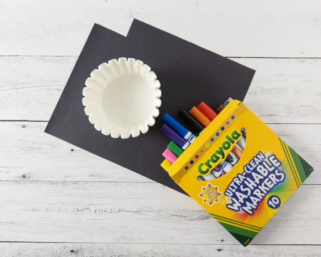 White basket coffee filters, box of washable markers, and black construction paper.