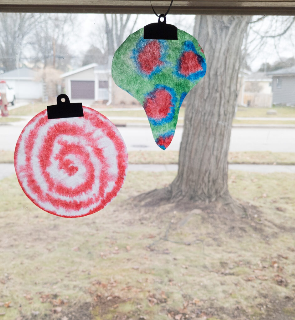 Two coffee filter ornament crafts hanging in the window.