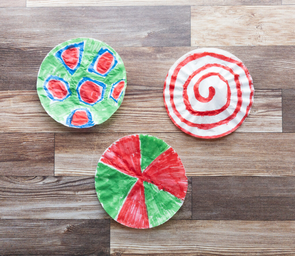 Three coffee filters colored with different patterns using red, green, and blue markers.