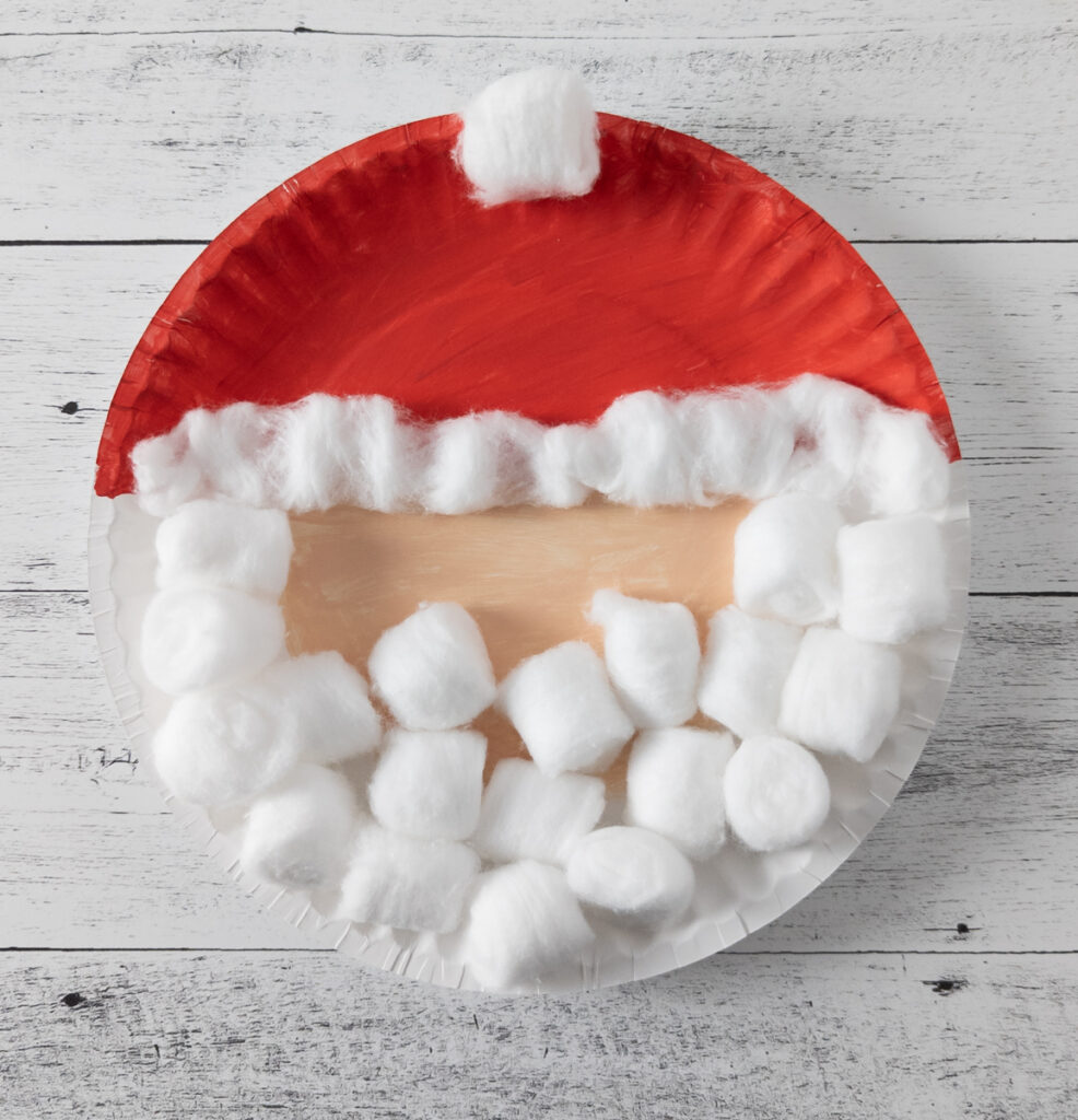 Adding cotton balls to Santa craft.