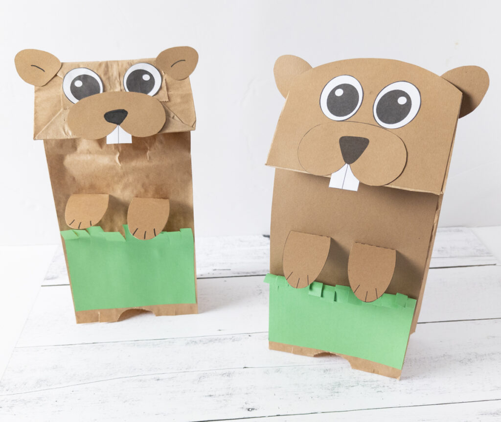 Two finished groundhog paper bag puppets standing up.