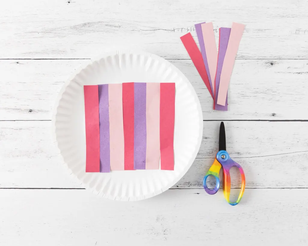 Red, purple, and pink construction paper cut into strips and glued across the middle of the plate.
