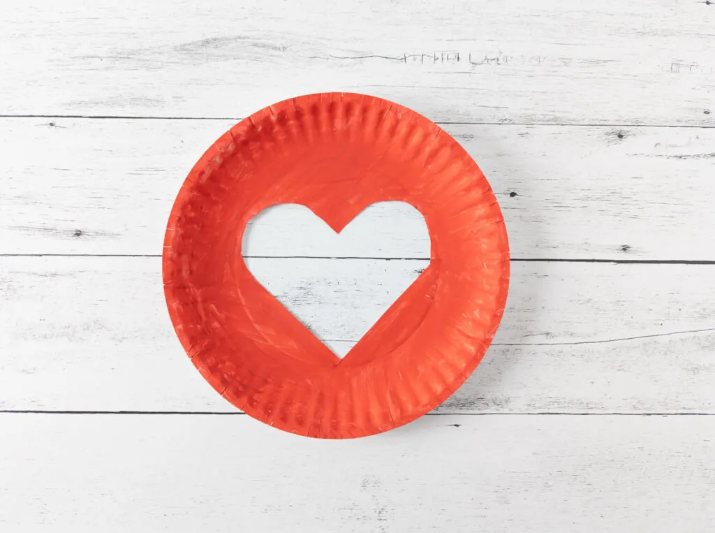Large paper plate painted red with a heart cut out of the center.