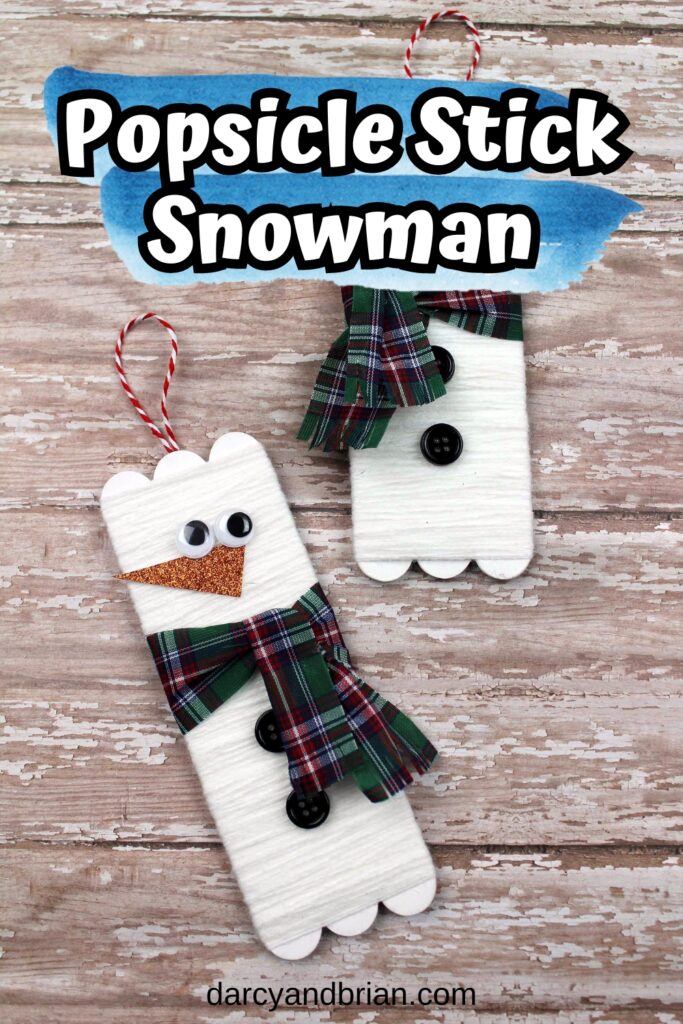 Completed popsicle stick snowman crafts laying on a wood background.