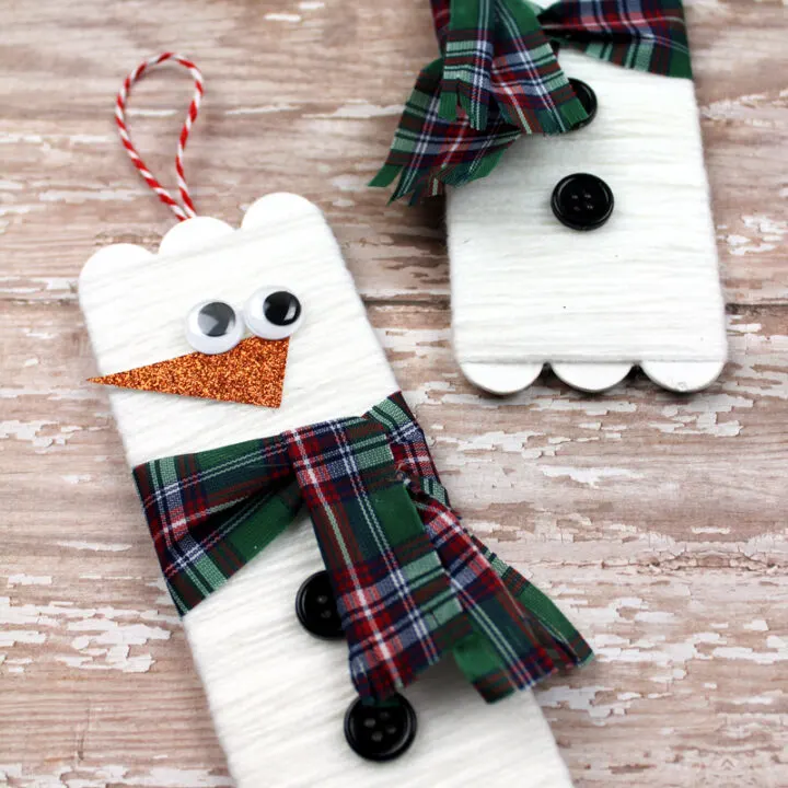 Two yarn wrapped snowman popsicle stick craft projects.