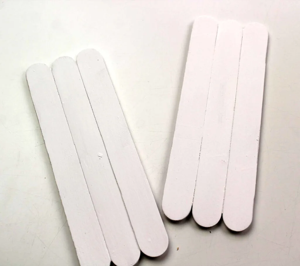 Two sets of three popsicle sticks glued together along the sides and painted white.