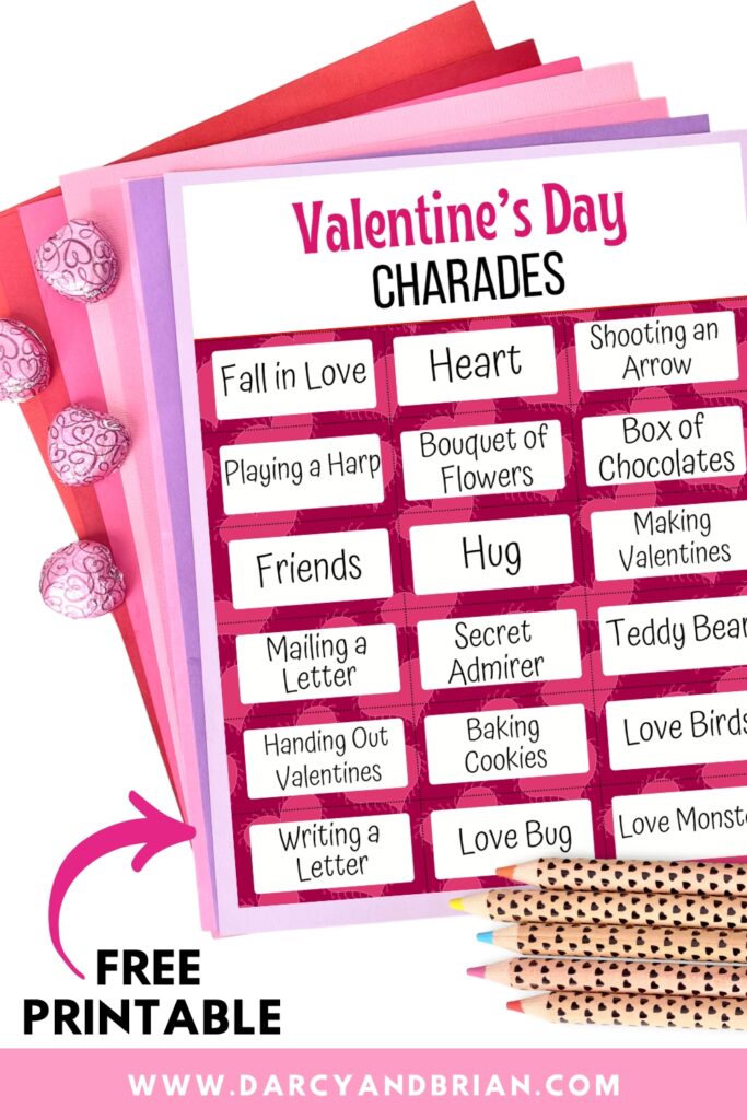 One page of Valentine charades on a stack of fanned out papers in pink, purple, and red colors. A few wrapped chocolates and pencils laying next to it.