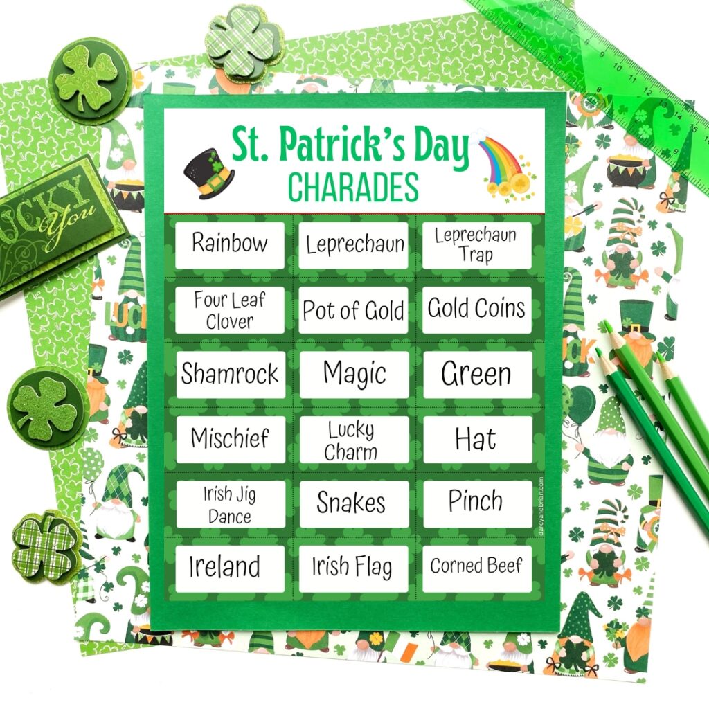 One page of charades cards with Saint Patrick's theme laying on top of green paper and decorative paper with gnomes and shamrocks. Assorted items around the sides: shamrock stickers, pencils, etc.