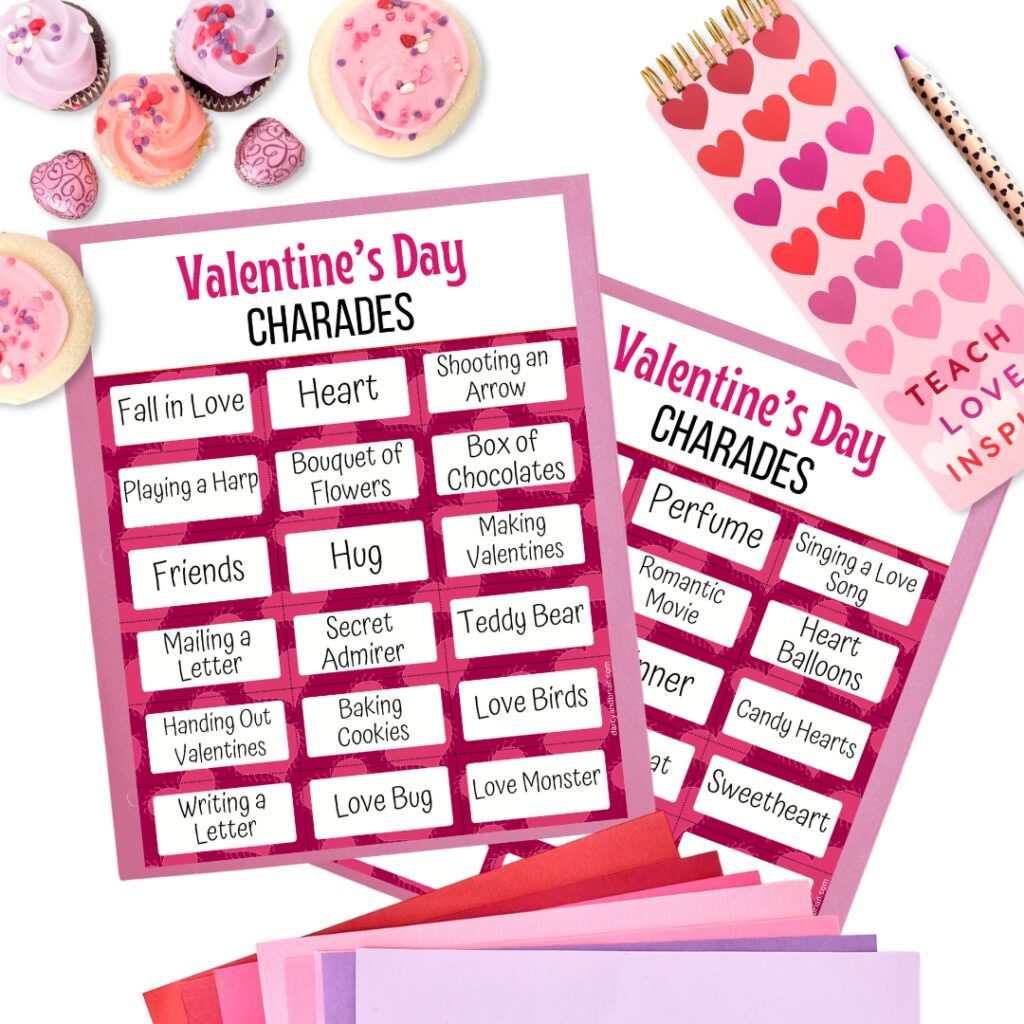 Preview of Valentine themed charades printable game surrounded by other valentine themed items such as pink cupcakes, paper in pink, red, and purple, and a notebook with hearts on it.