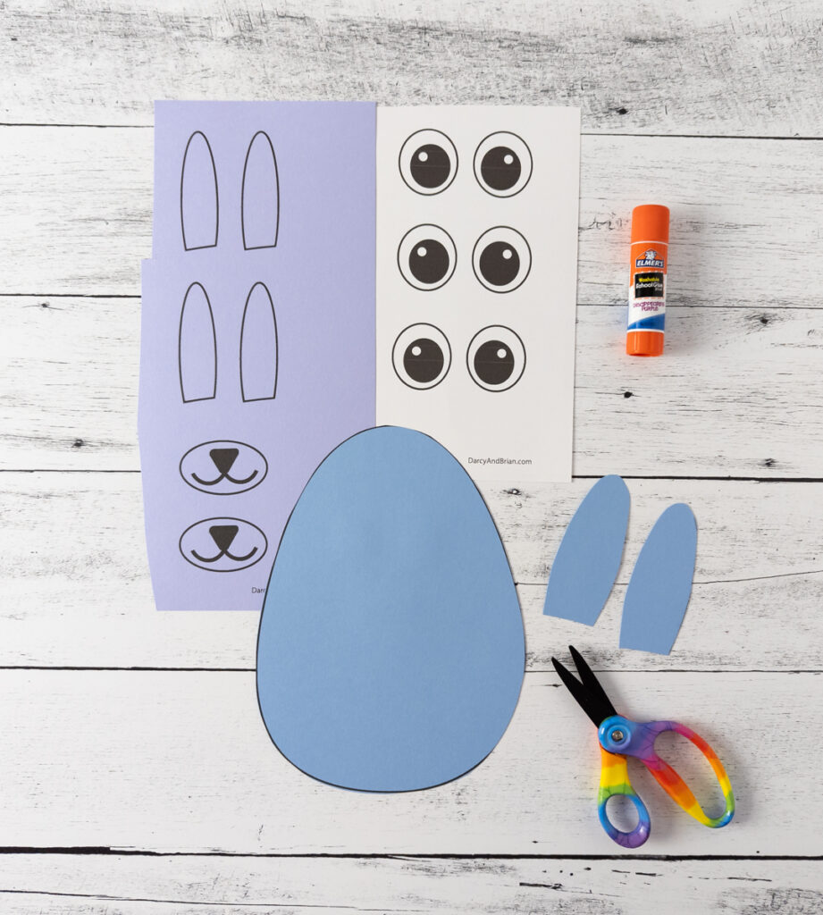 Purple paper with mouth and inner ear template printed out. Paper googly eyes printed on white cardstock. Egg shaped cut out of blue paper and ears too.