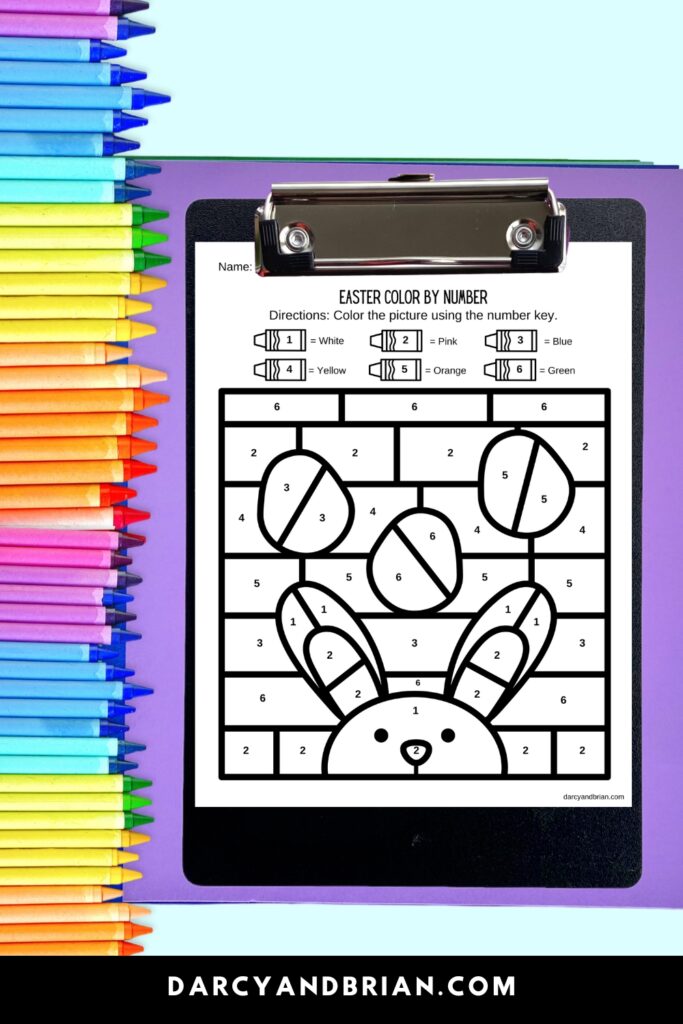 Bunny with eggs color by number coloring page on a clipboard with crayons along the side.