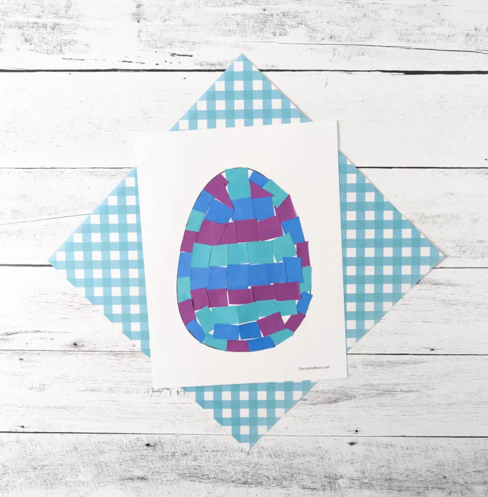 Overhead view of Easter egg template filled with blue and purple paper squares.