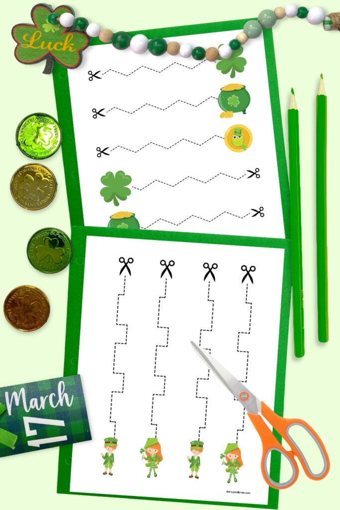 Mockup of two scissor cutting pages with Saint Patrick's Day themed pictures laying on top of green paper. Coins and shamrocks decorate the image. A pair of scissors and two green pencils lay by the papers.