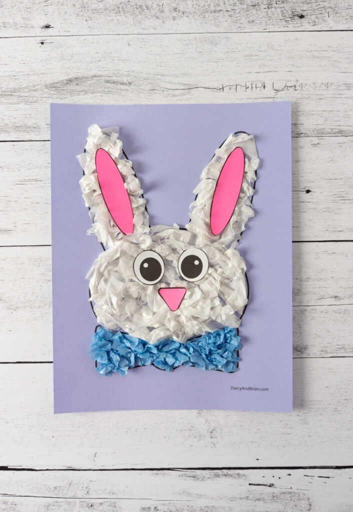 White tissue paper covered Easter bunny template with pink inner ear pieces, pink nose, and paper eyes glued onto face.
