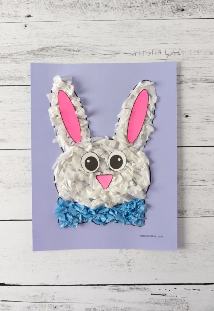 White tissue paper covered Easter bunny template with pink inner ear pieces, pink nose, and paper eyes glued onto face.