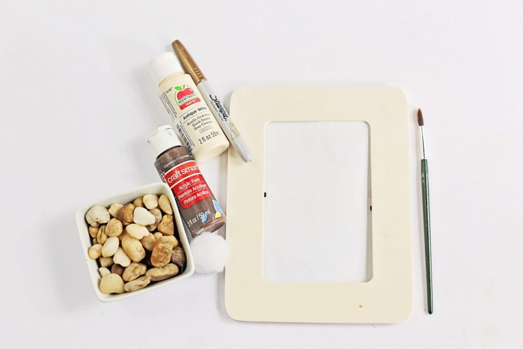 Supplies for My Dad Rocks craft includes a wooden frame, brown paint, white paint, a marker, and a box of rocks.