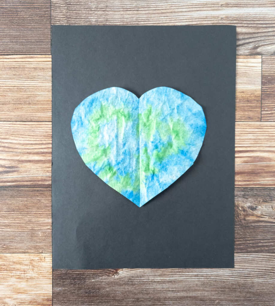 Blue and green colored coffee filter cut into a heart glued to black paper.