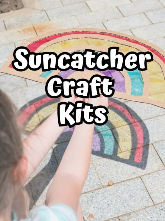 Child holding out a rainbow suncatcher made with cardboard and clear plastic making a colorful rainbow on the sidewalk. White text in the center says Suncatcher Craft Kits