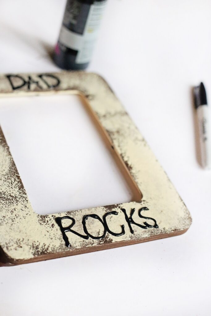 Close view of black puffy paint used to write Dad Rocks on the painted photo frame.