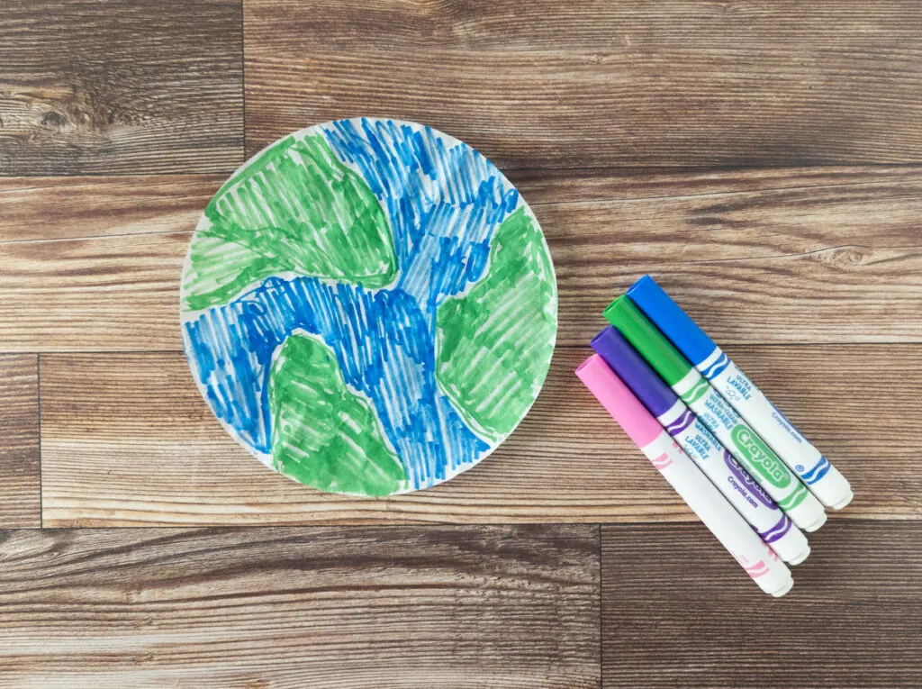 Round coffee filter colored with blue and green markers to look like planet Earth.